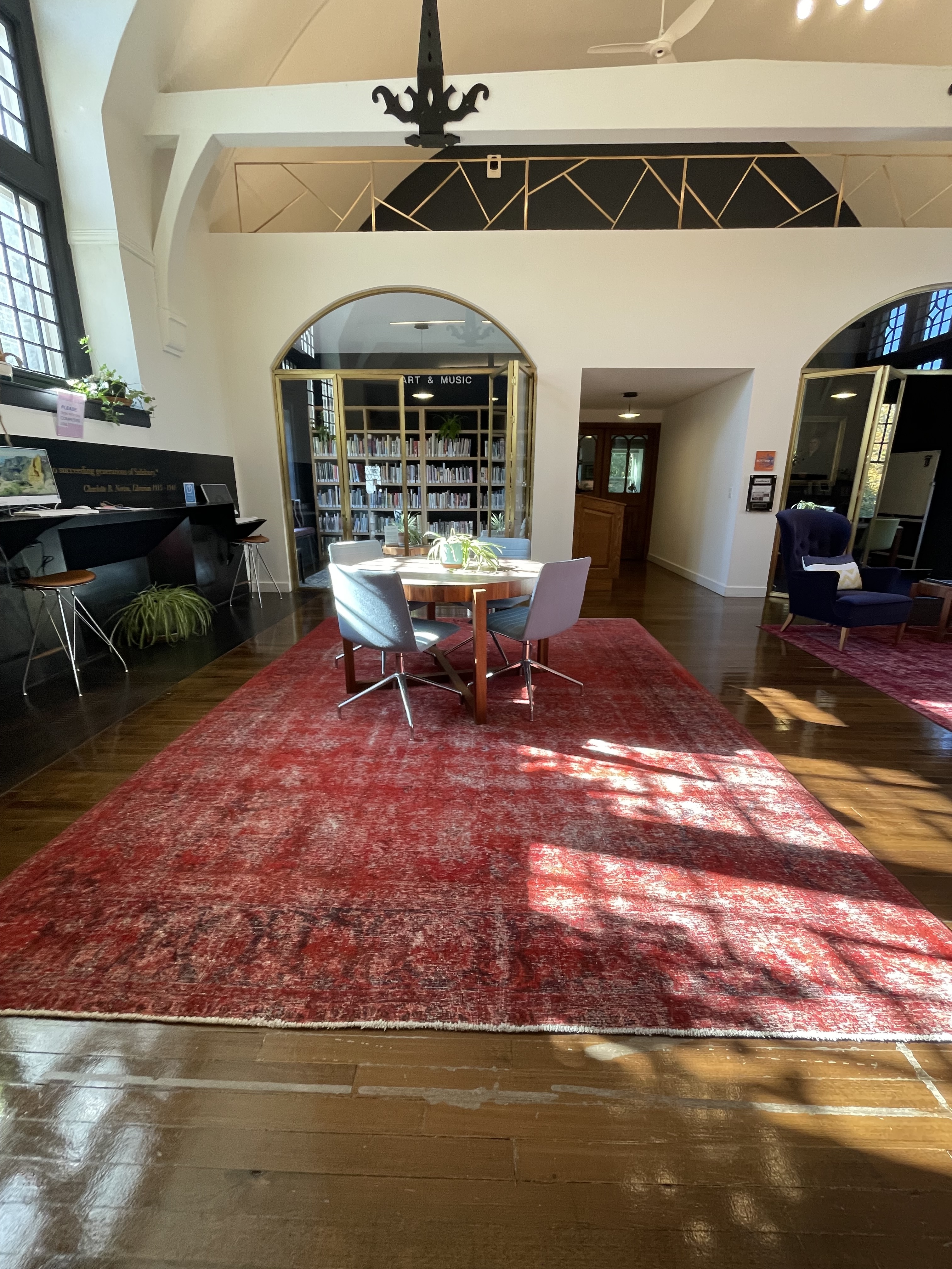 Open work space with red rug, table, bar seating with computers
