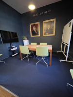 Blue meeting room with portraits, white board, table and chairs, display screen