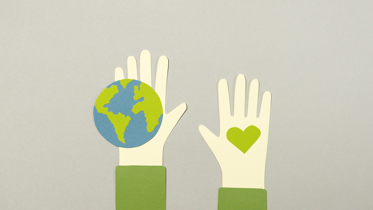 two hands, one holding a small globe, the other a small green heart